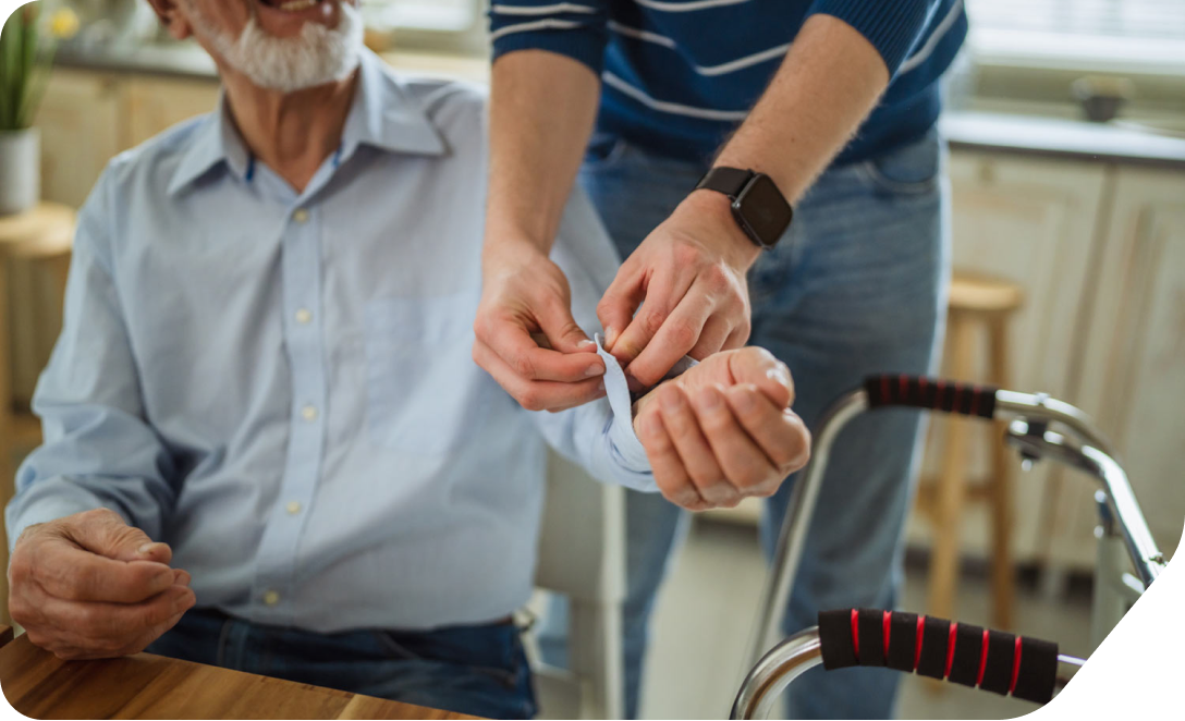 Helping an elderly man with a button on their shirt