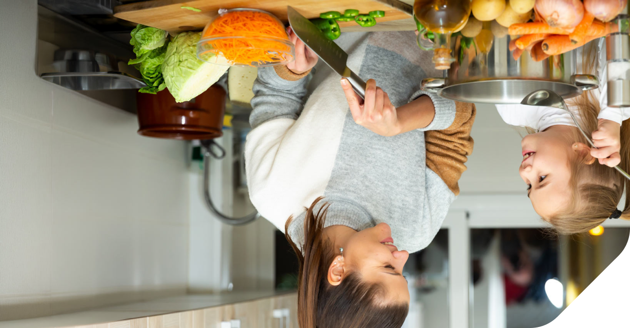 A young mother and child in their kitchen eating healthy vegetables.